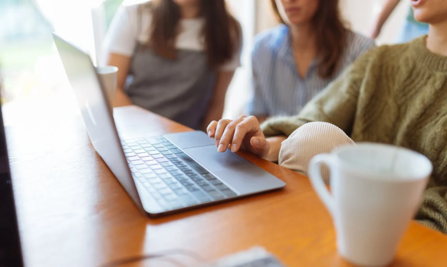 A person using a laptop, sitting next to two people