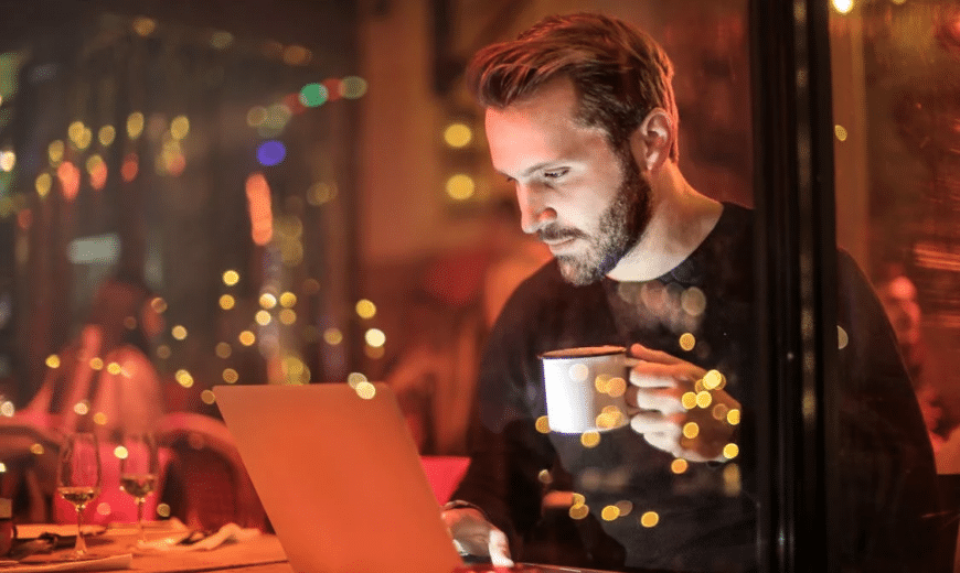 A man on his laptop, holding a mug