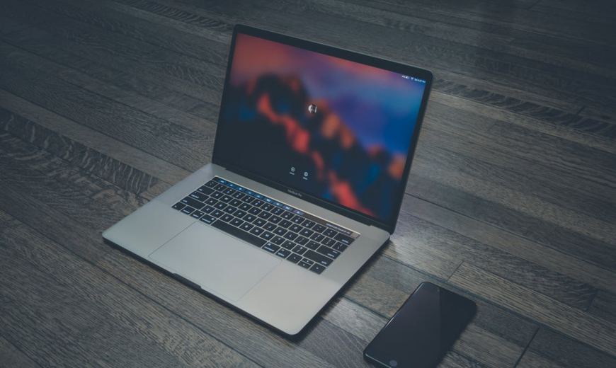 A silver laptop next to a black smartphone