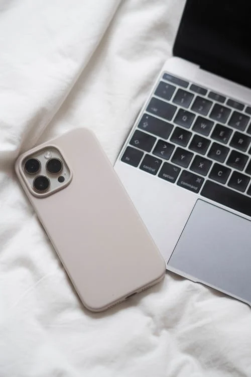 A laptop and an iPhone case on a bed