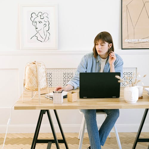 A woman sitting at a desk, with a laptop open