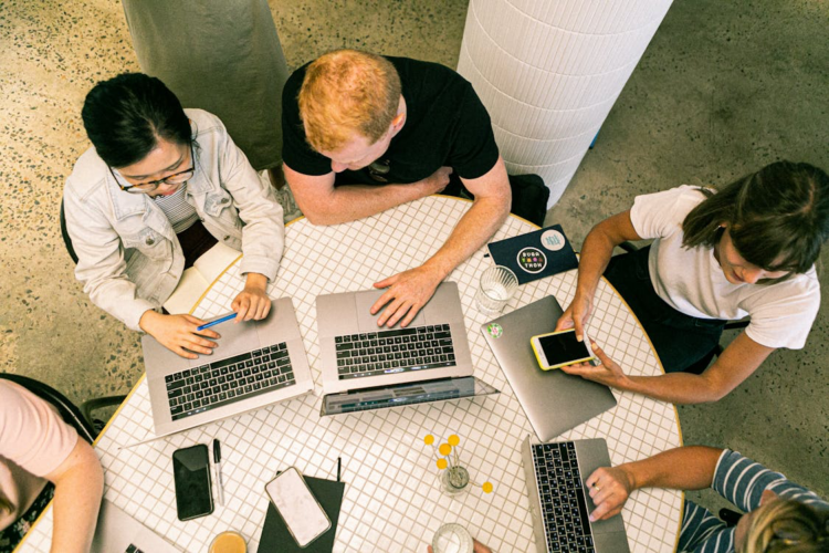 A group of people sitting a table, using laptops