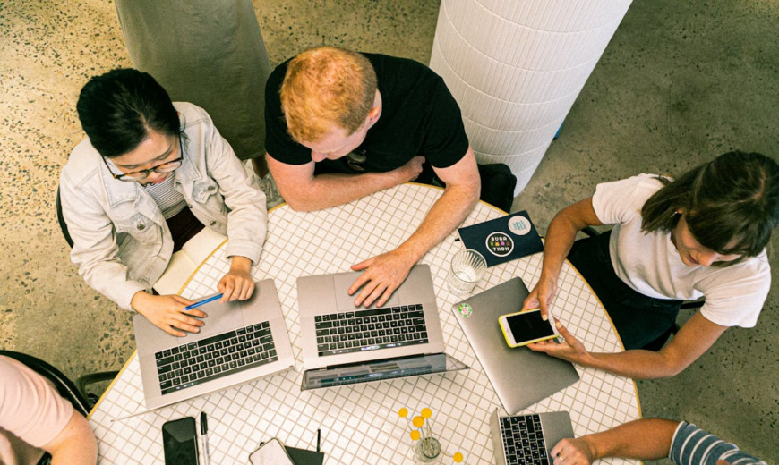 A group of people sitting a table, using laptops