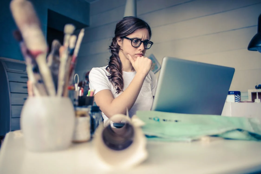 A woman thinking, while looking at a laptop screen