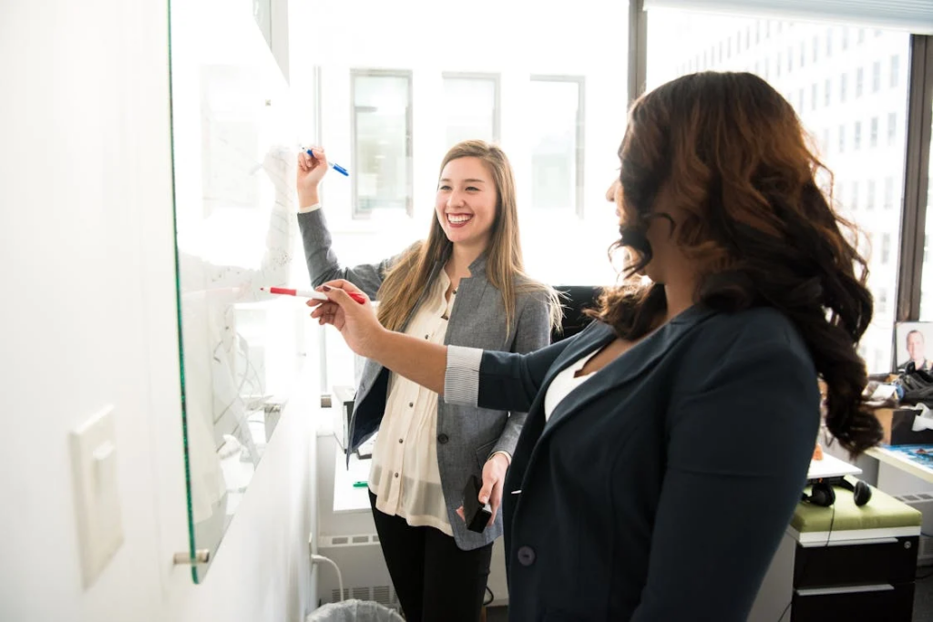 Two women using a dry-erase board 