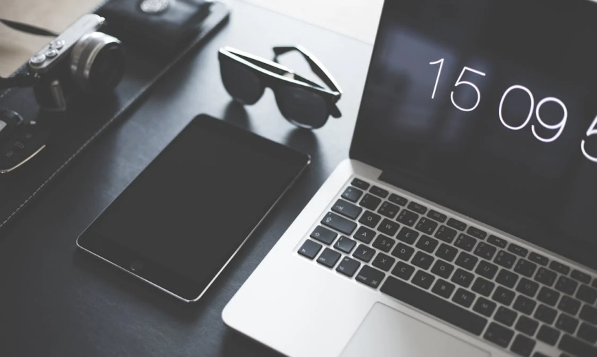 A laptop and iPad next to a pair of sunglasses