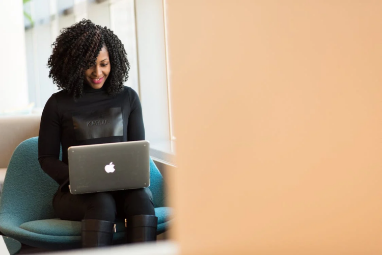 A woman sitting on a blue chair, using a laptop