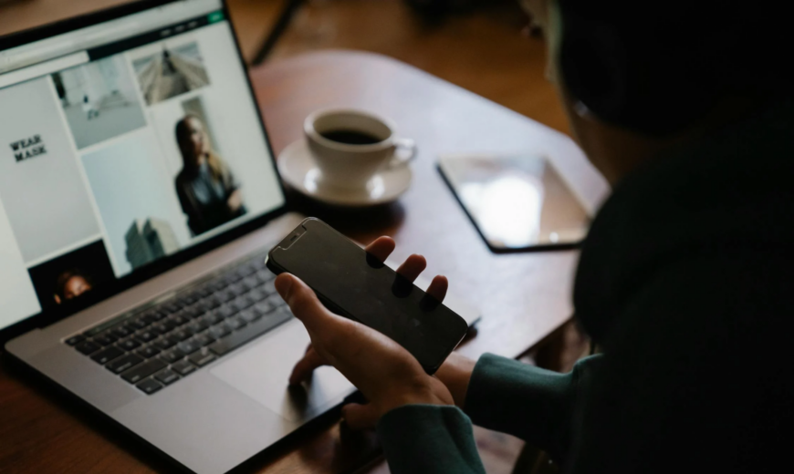 A man using a laptop and smartphone